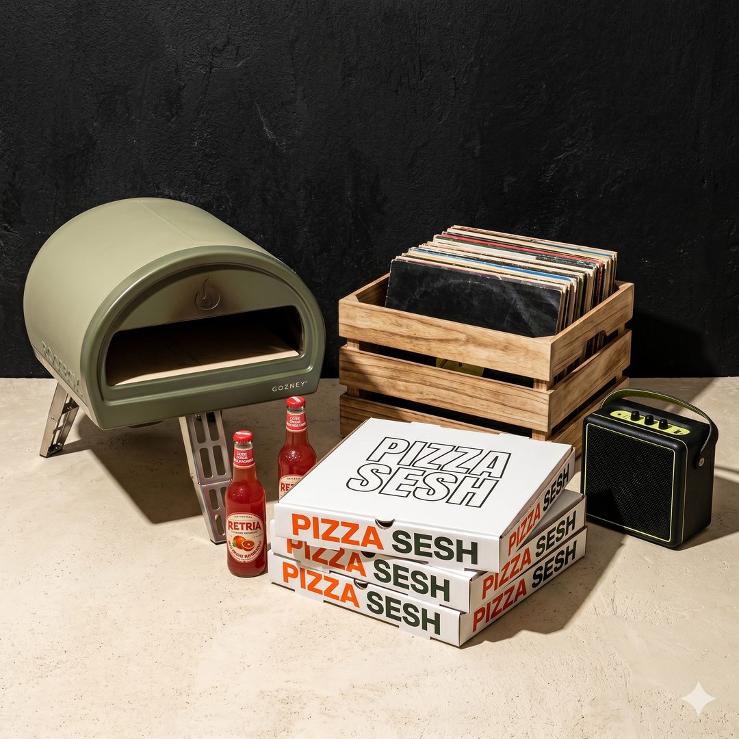 Olive Gozney pizza oven beside a crate of vinyl records, stacked Pizza Sesh boxes, blood-orange sodas and a speaker
